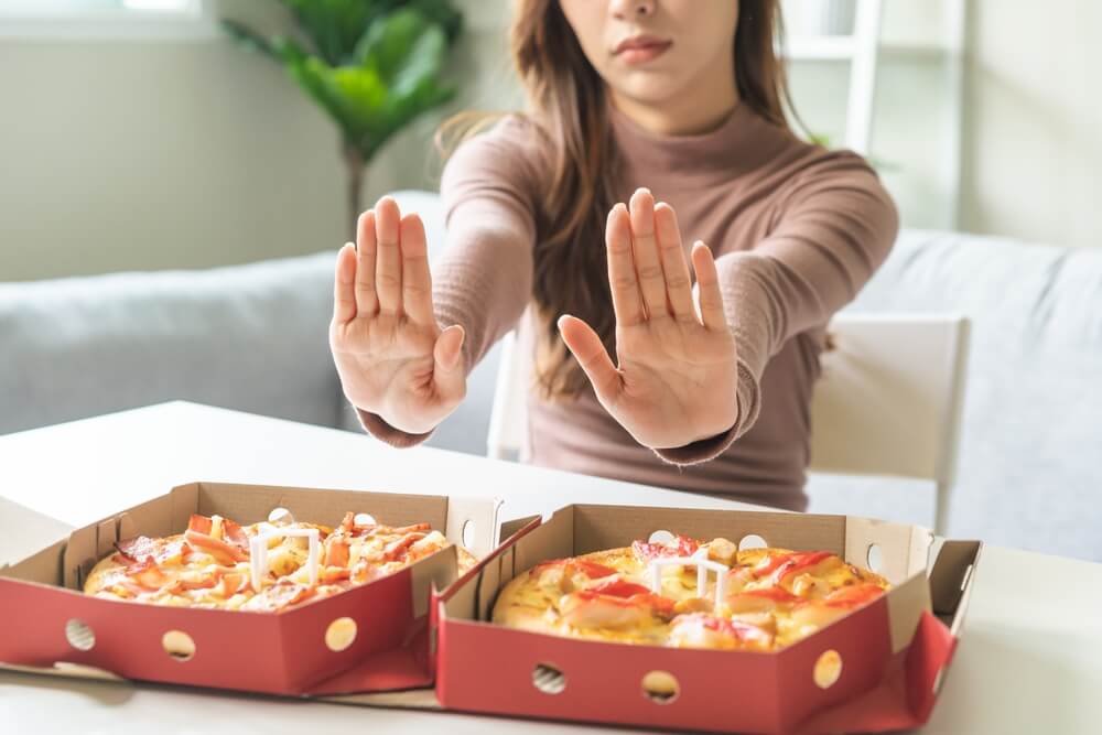 Young woman refuses pizza worst processed ingredients and preservatives for diet