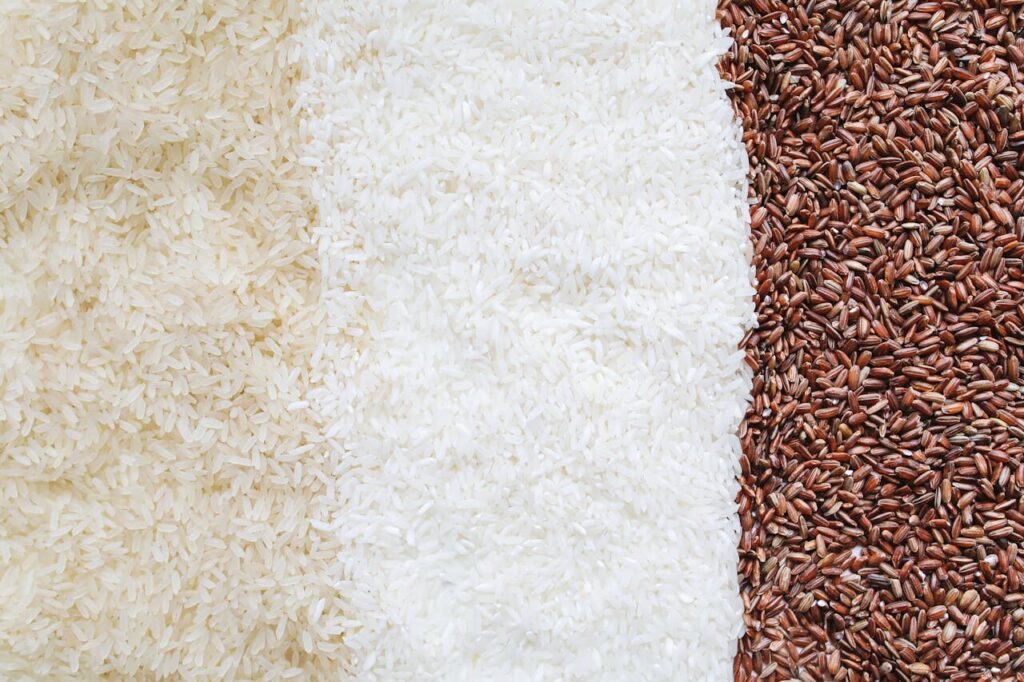 Tasty cooked rice in bowl on bamboo mat, top view